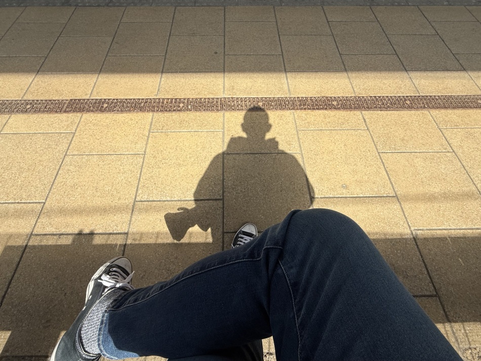 My shadow cast onto the platform as I sit on a bench at Leeds station