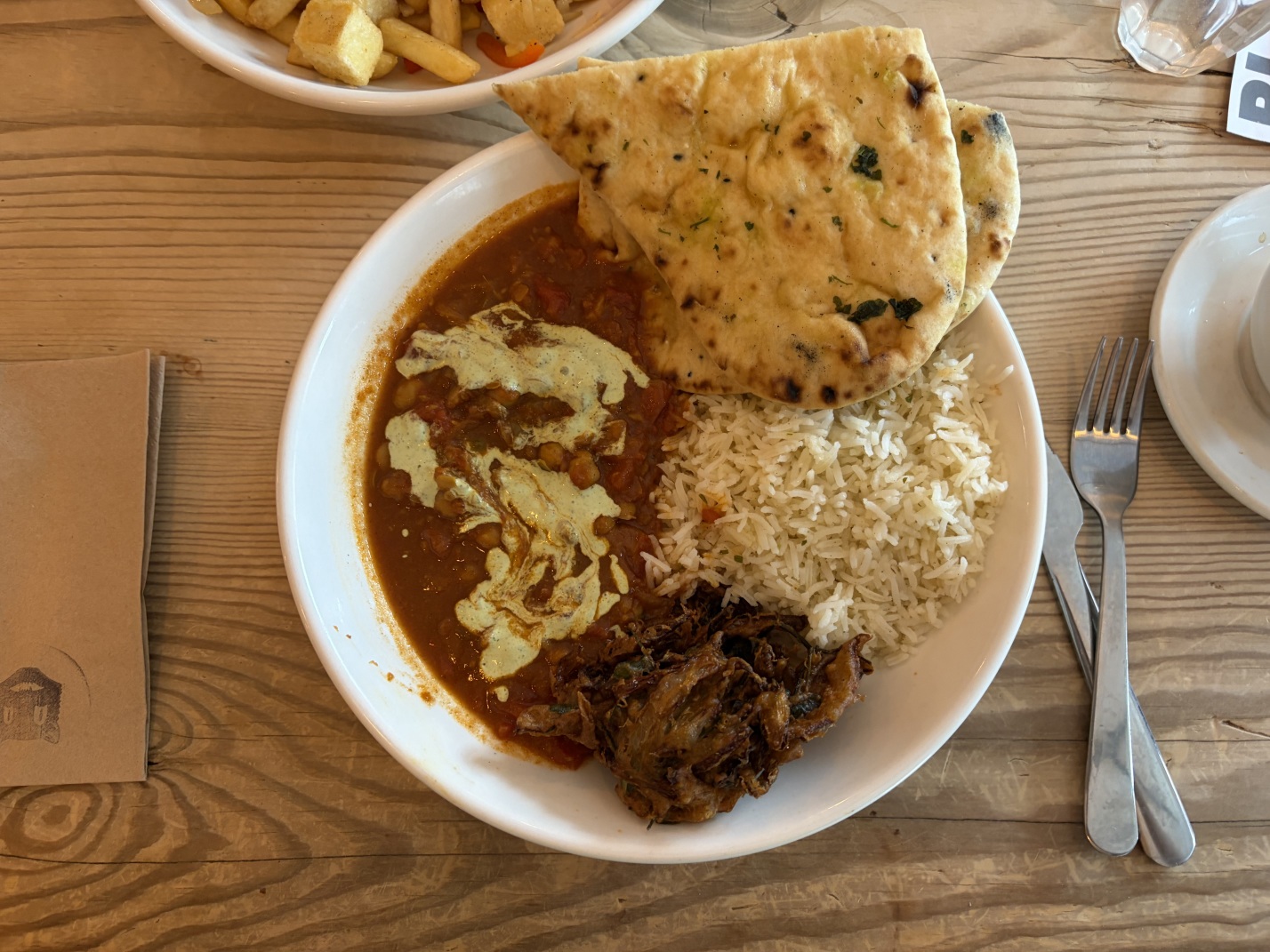 Chana masala with naan, rice and pakora, with some chips and tofu poking into frame