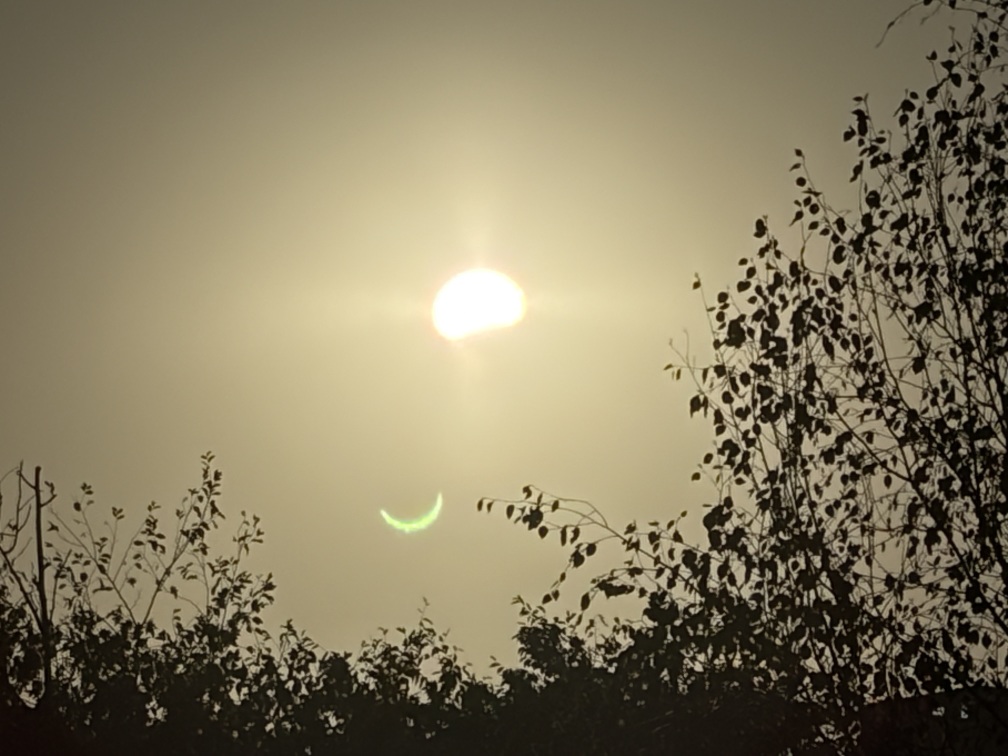 A photo of the eclipse, indistinguishable from a normal photo of the sun except for the cheeky crescent lens flare