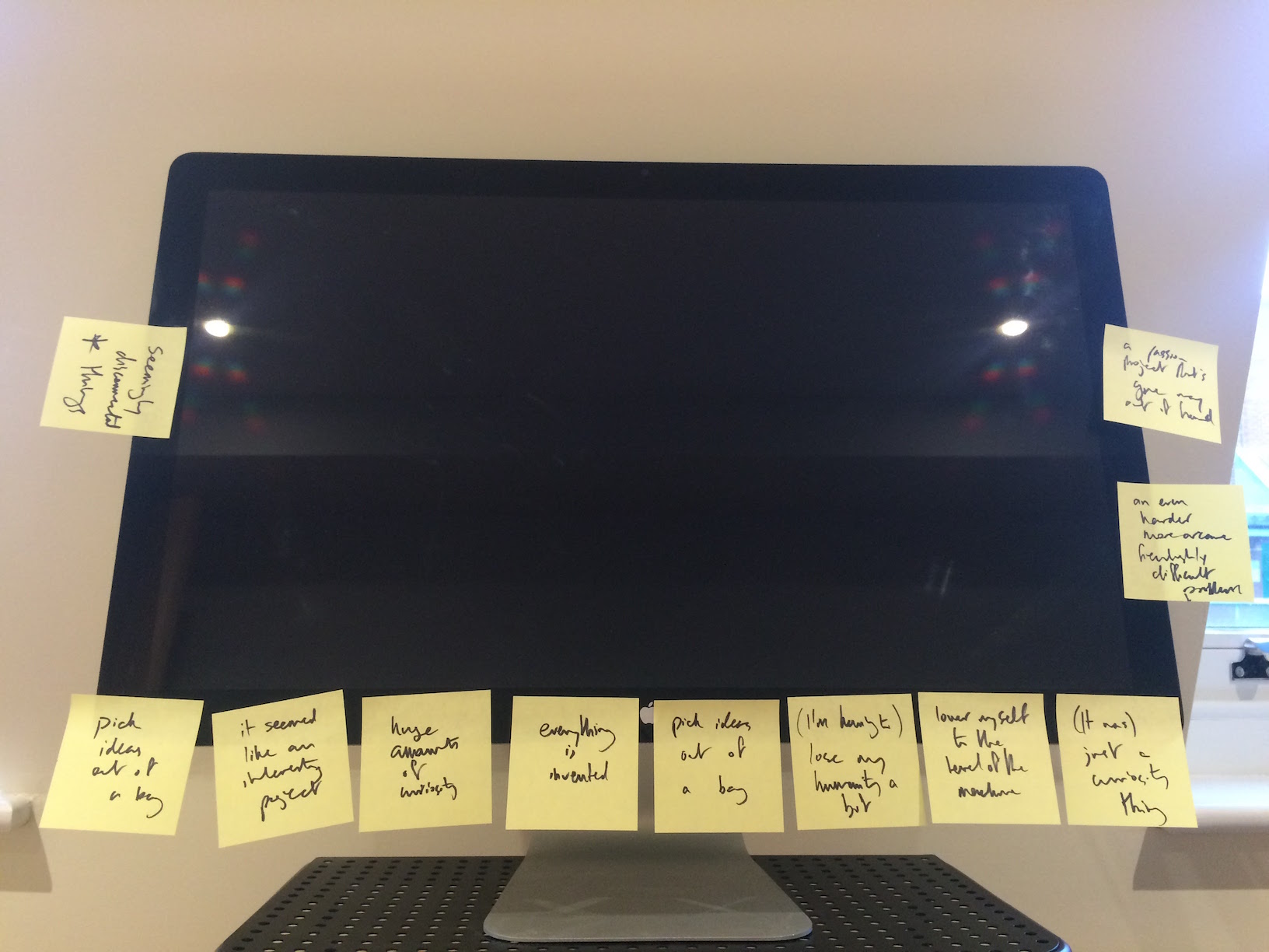 A monitor with many Post-it notes attached: “seemingly disconnected things”, “pick ideas out of a bag”, “it seemed like an interesting project”, “huge amounts of curiosity” etc